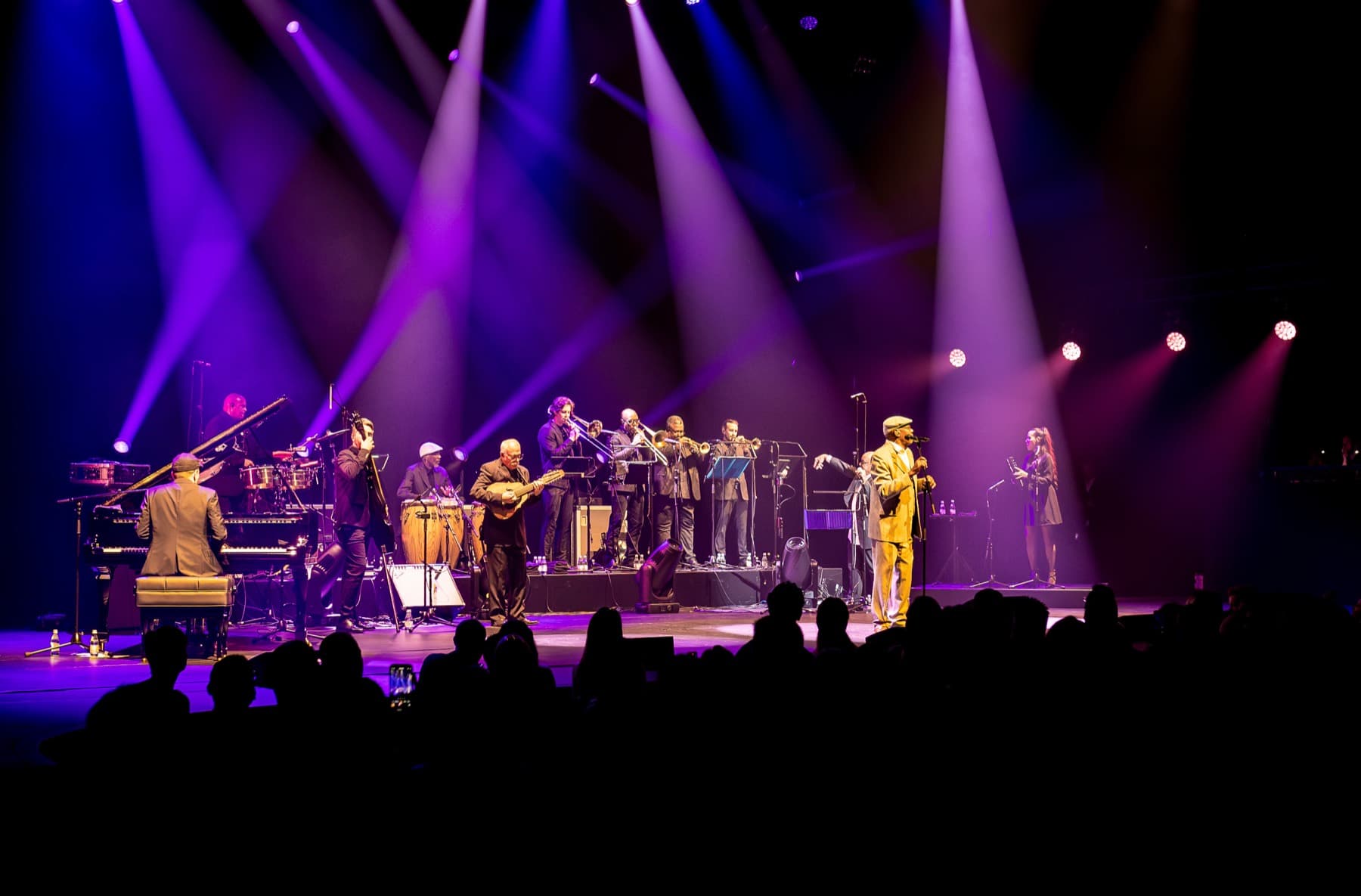 Band on stage under purple and white beams
