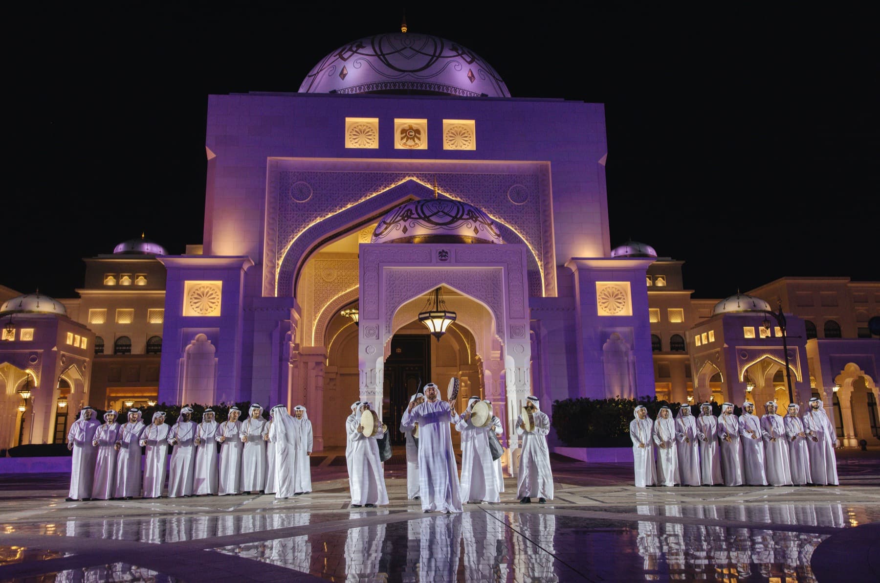 Traditional performers before the illuminated Qasr Al Watan palace