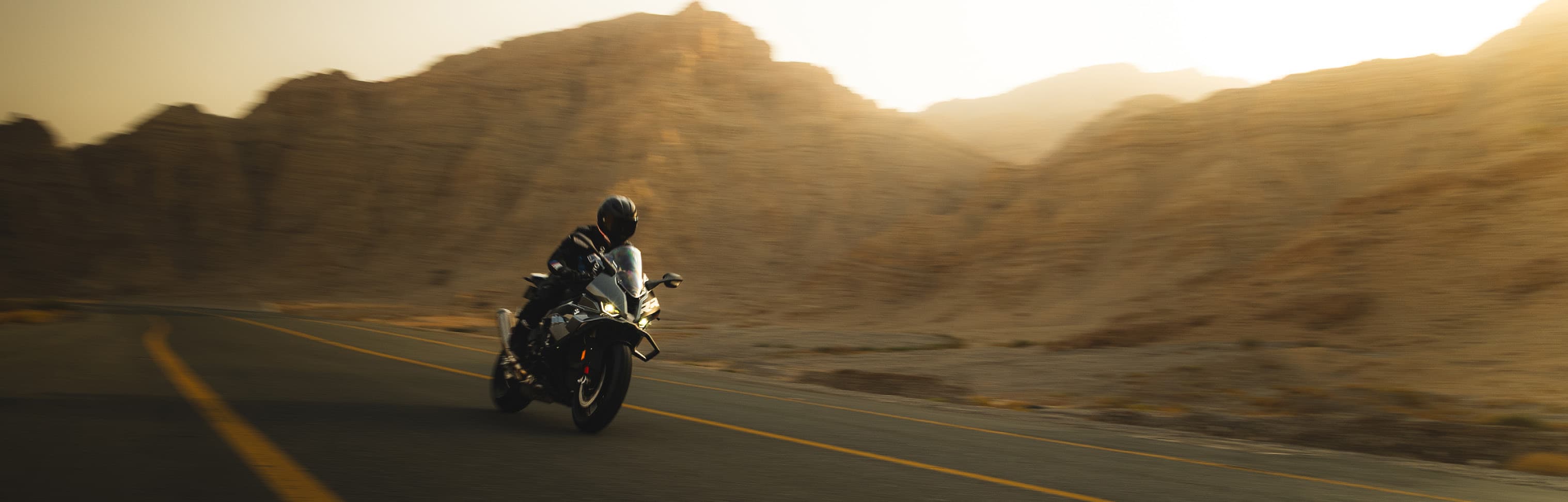 Motorcyclist leaning through a mountain road at dusk
